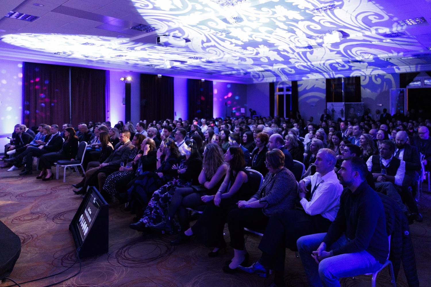 Salle de plénière d'hôtel pleine pendant une convention d'entreprise, plafond éclairé