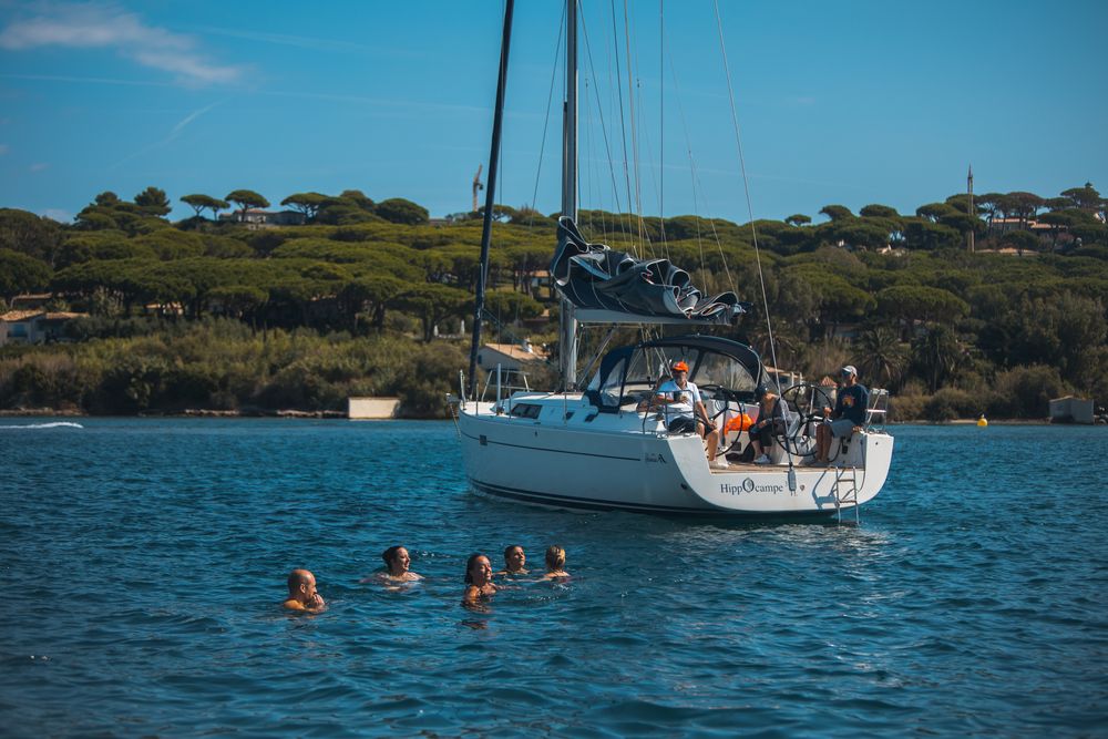 Baignade autour d'un voilier au mouillage, devant une pinède