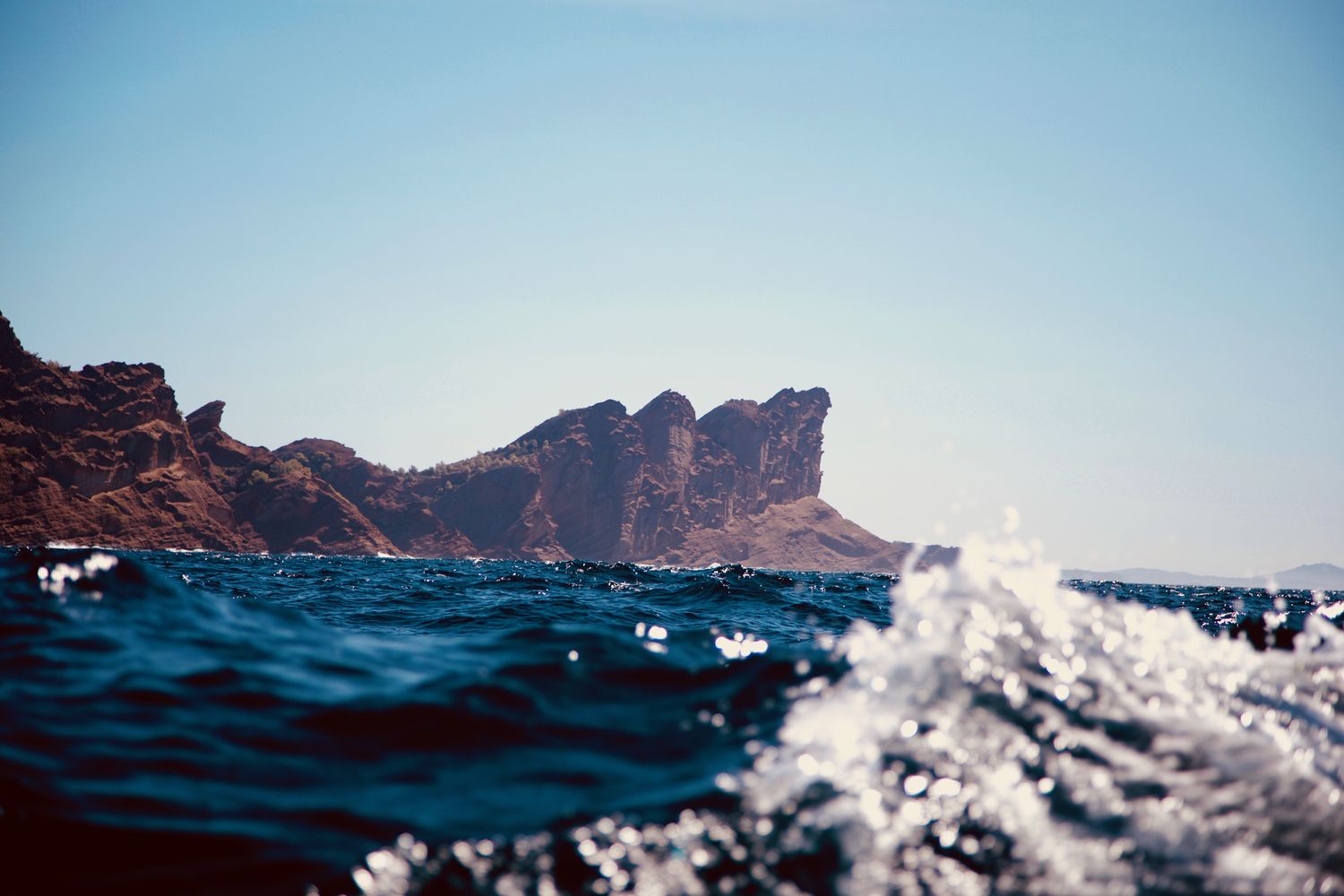 Les falaises rouges du Bec de l'Aigle depuis un bateau, dans le sillage