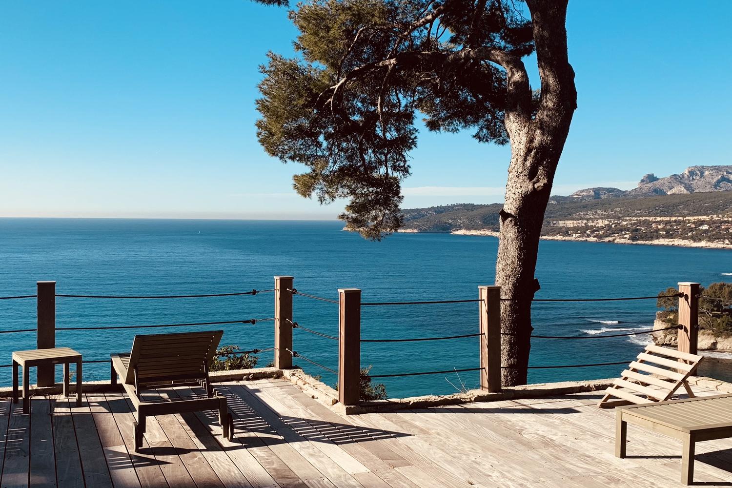 Terrasse en bois sous un pin, face à la baie de Cassis et au cap Canaille