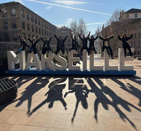 Une équipe saute devant les lettres géantes du panneau Marseille